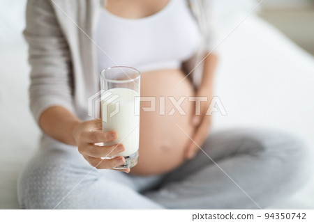 Unrecognizable pregnant woman holding glass of milk, cropped 94350742