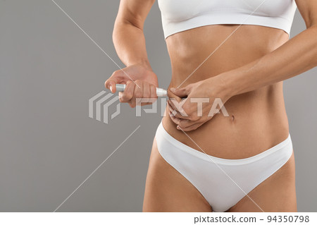 Insulin Dependence. Slim young woman in underwear making insulin injection to waist side 94350798