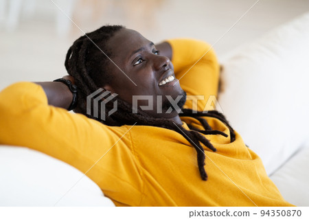 Home Rest. Portrait Of Smiling Young Black Man Leaning Back On Couch 94350870