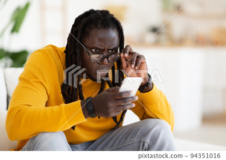 Bad Vision. Black Guy In Eyeglasses Looking At Smartphone Screen At Home Bad Vision. Black Guy In Eyeglasses Looking At Smartphone Screen At Home 94351016