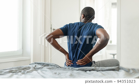 African Man Having Pain Touching Lower Back Sitting In Bedroom 94351023