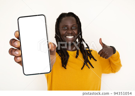Positive Young Black Guy Holding Blank Smartphone And Showing Thumb Up Gesture Positive Young Black Guy Holding Blank Smartphone And Showing Thumb Up Gesture 94351054