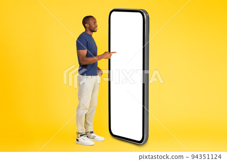 African American Male Using Large Smartphone Empty Screen, Yellow Background African American Male Using Large Smartphone Empty Screen, Yellow Background 94351124