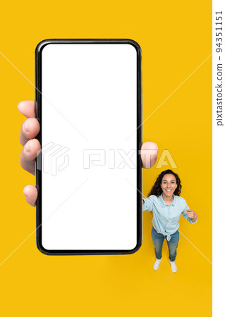 Lady Showing Large Phone With Empty Screen, Yellow Background, Vertical Lady Showing Large Phone With Empty Screen, Yellow Background, Vertical 94351151