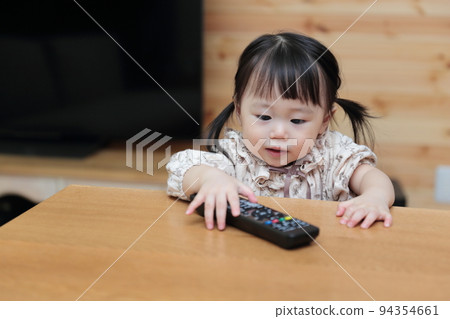A 1-year-old girl pranking the TV remote control A 1-year-old girl pranking the TV remote control 94354661