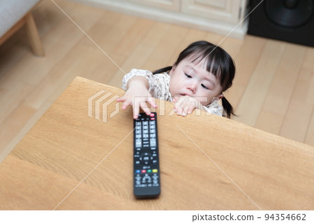 A 1-year-old girl pranking the TV remote control A 1-year-old girl pranking the TV remote control 94354662