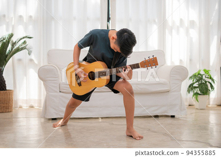 Portrait of a Asian happy smiling boy having fun playing guitar Music concept, kids music school. Rock concert, Music for kids and toddlers concept Portrait of a Asian happy smiling boy having fun playing guitar Music concept, kids music school. Rock concert, Music for kids and toddlers concept 94355885
