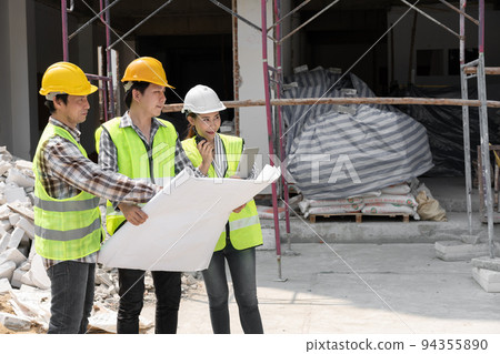 Asian engineer or Young Female Architect put on a helmet for safety and talk with a contractor on a construction building factory project, Concept of Teamwork, Leadership concept. 94355890