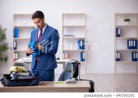 Young male employee preparing for trip at workplace 94356191