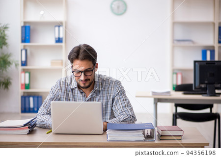 Young male employee sitting in the office Young male employee sitting in the office 94356198