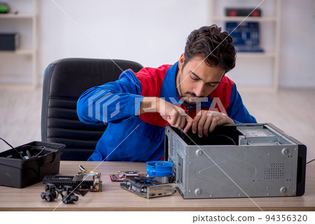Young male repairman repairing computer Young male repairman repairing computer 94356320