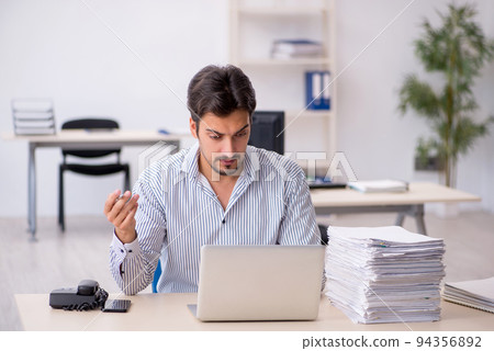Young male employee and too much work in the office 94356892