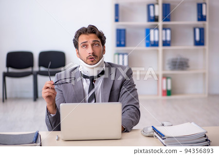 Young male employee after car accident working in the office 94356893
