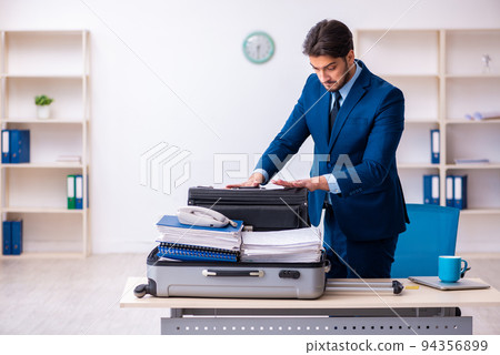 Young male employee preparing for business trip at workplace Young male employee preparing for business trip at workplace 94356899