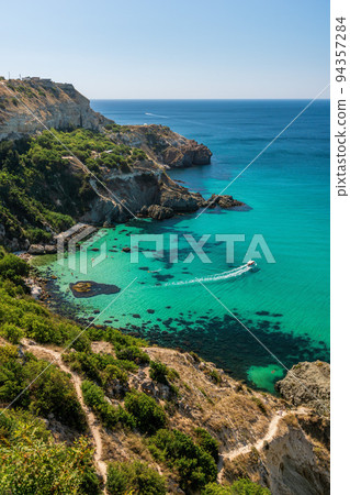 yachts on Baunty beach, cape Fiolent in Balaklava, Sevastopol, Russia. View from the top of the rock. azure sea, sunny day clear sky background. The concept of perfect place for summer travel and rest 94357284