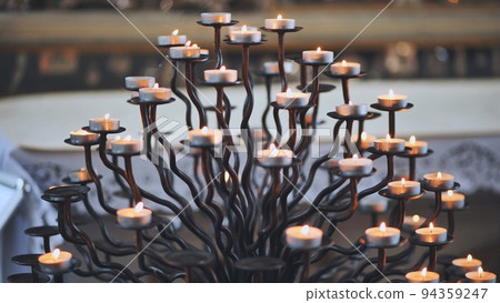 Candlestick holder with burning candles in a Catholic church. Candlestick holder with burning candles in a Catholic church. 94359247