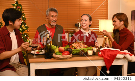 Joyful family talking and celebrating Christmas at dining table. Holidays and celebration concept 94360311
