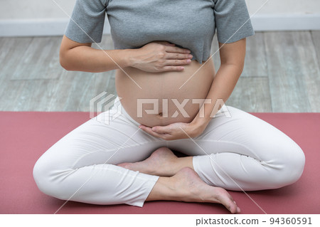 Happy Calm Pregnant Woman sit on yoga mat and stroking her big belly with love at cozy home,Pregnancy of young woman enjoy with yoga to breathing and meditation at home,Motherhood and Pregnant Concept Happy Calm Pregnant Woman sit on yoga mat and stroking her big belly with love at cozy home,Pregnancy of young woman enjoy with yoga to breathing and meditation at home,Motherhood and Pregnant Concept 94360591