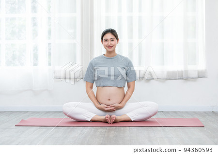 Happy Calm Pregnant Woman sit on yoga mat and stroking her big belly with love at cozy home,Pregnancy of young woman enjoy with yoga to breathing and meditation at home,Motherhood and Pregnant Concept Happy Calm Pregnant Woman sit on yoga mat and stroking her big belly with love at cozy home,Pregnancy of young woman enjoy with yoga to breathing and meditation at home,Motherhood and Pregnant Concept 94360593