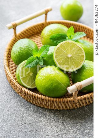 Green Limes with fresh mint leaves on wicker tray Green Limes with fresh mint leaves on wicker tray 94362274