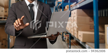 Storage worker in uniform Wearing Hard Hat Checks Stock and Inventory with Digital Tablet Computer in the Retail Warehouse full of Shelves with Goods. . Storage worker in uniform Wearing Hard Hat Checks Stock and Inventory with Digital Tablet Computer in the Retail Warehouse full of Shelves with Goods. . 94362806