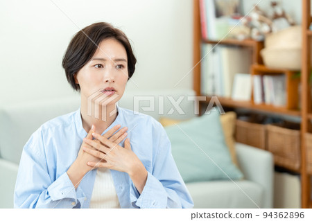 A woman who puts her hand on her chest in the living room 94362896