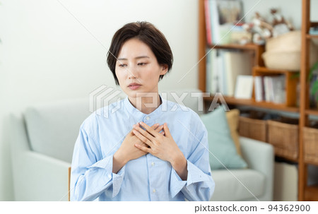 A woman who puts her hand on her chest in the living room 94362900