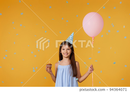 happy little birthday girl with party cone holding cupcake happy little birthday girl with party cone holding cupcake 94364071