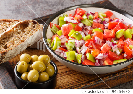 Trampo ensalada salad made with tomatoes, peppers, and onions served with olive and bread closeup on the wooden board. Horizontal 94364680