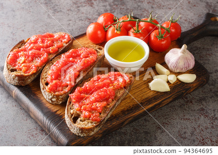 Catalonian cuisine Pan Con tomate, bread with tomato and garlic closeup on the wooden board. Horizontal 94364695