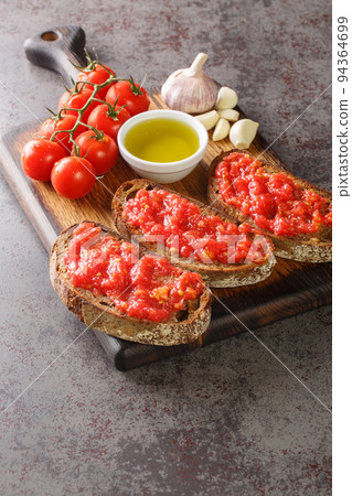 Pa amb tomaquet or tomaca bread with tomato also known as pan con tomate and tostada closeup on the wooden board. Vertical Pa amb tomaquet or tomaca bread with tomato also known as pan con tomate and tostada closeup on the wooden board. Vertical 94364699