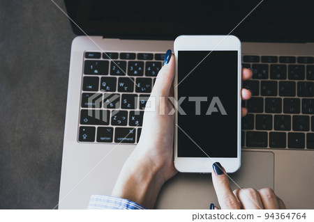Woman operating a laptop and smartphone - Stock Photo