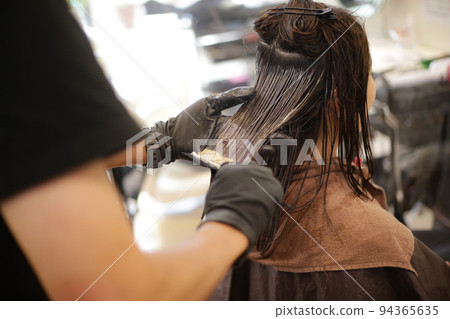 男理髮師在女人的頭髮上塗藥 94365635