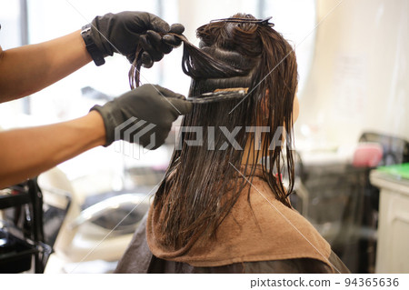 Male hairdresser applying drug to woman's hair 94365636