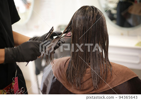 Male hairdresser applying drug to woman's hair Male hairdresser applying drug to woman's hair 94365643