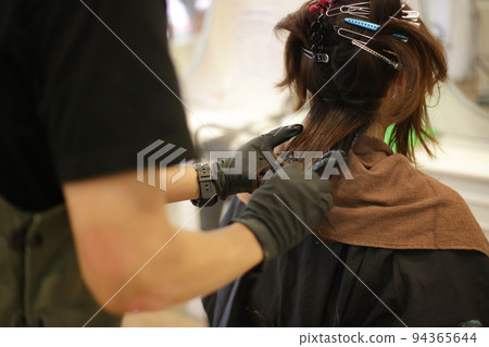 Male hairdresser applying drug to woman's hair Male hairdresser applying drug to woman's hair 94365644