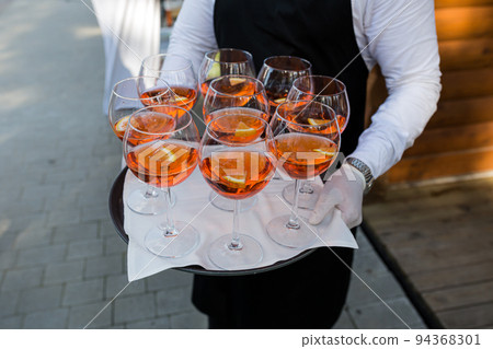 The waiter greets guests, a close-up photo of glasses with the drink Aperol 94368301