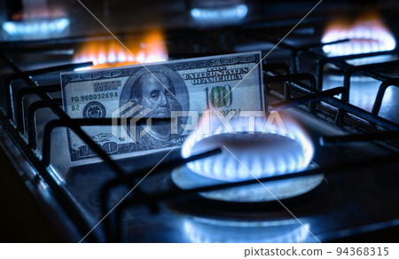 Gas burners and US dollar bill, USA money on home gas stove Gas burners and US dollar bill, USA money on home gas stove 94368315
