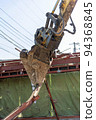 Small demolition machine that grabs steel scraps at the demolition site 94368845