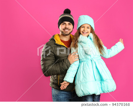 Happy father and daughter in warm clothes on pink background. Winter vacation Happy father and daughter in warm clothes on pink background. Winter vacation 94370168
