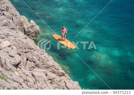 Young women Having Fun Stand Up Paddling in blue water sea in Montenegro. SUP. girl Training on Paddle Board near the rocks Portrait of a disgruntled girl sitting at a cafe table Young women Having Fun Stand Up Paddling in blue water sea in Montenegro. SUP. girl Training on Paddle Board near the rocks Portrait of a disgruntled girl sitting at a cafe table 94371221