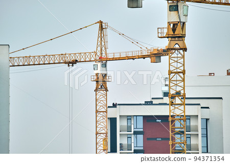 Tower cranes at high residential apartment buildings construction site. Real estate development Tower cranes at high residential apartment buildings construction site. Real estate development 94371354