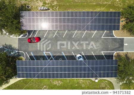 Solar panels installed over parking lot for parked cars for effective generation of clean energy 94371382