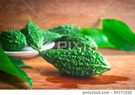 Wild bitter gourd on a wooden background. 94371898