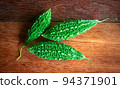 Wild bitter gourd on a wooden background. 94371901