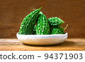 Wild bitter gourd on a wooden background. 94371903
