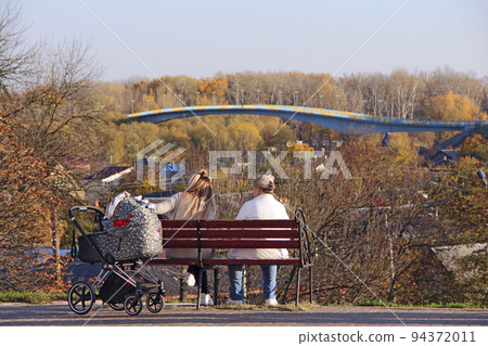 Mom with baby carriage and grandmother have a rest in park. Three generations 94372011