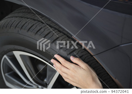 Female driver hands inspecting wheel tire of her new car. Vehicle safety concept 94372041