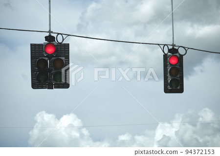 Bright red stop traffic lights high above street on blue sky background 94372153