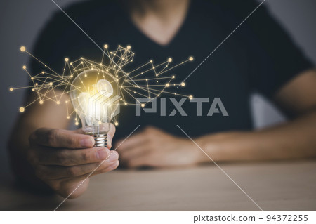 Businessman hand holding light bulb with icons and working on the desk, Creativity and innovation are keys to success.Concept of new idea and innovation with energy and power , working at home, 94372255